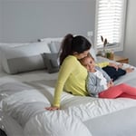 Mother and child lounging on a bed after it’s been Electrodry Cleaned.