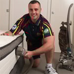 Technician vacuuming a mattress using a HEPA filter.