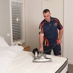 Technician vacuuming a mattress using a HEPA filter.